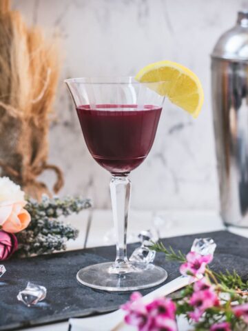 Elegant, dark red beetroot sour, garnished with a lemon wedge. Placed on a black slate plate.