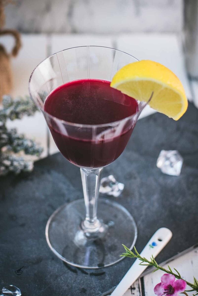 Elegant, dark red beetroot sour, garnished with a lemon wedge. Placed on a black slate plate.