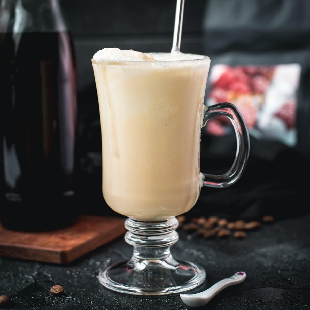 Serving glass filled with homemade coffee milkshake, topped with cold frothed milk and served with a reusable drinking straw.
