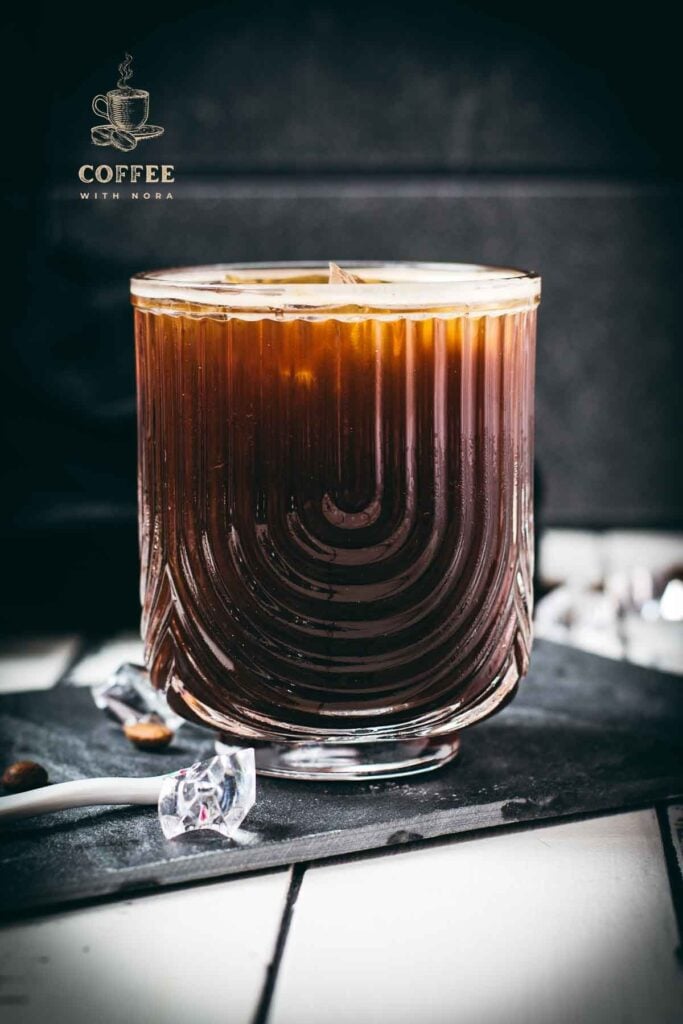 Stunning and delicious iced Americano, served in a gorgeous glass and placed on a black slate plate.