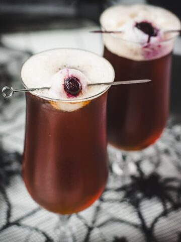 Spooky black velvet cocktail, garnished with eerie lychee eyeballs.