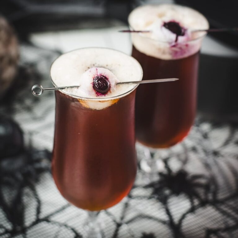 Spooky black velvet cocktail, garnished with eerie lychee eyeballs.