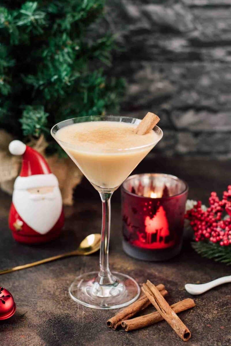 Delicious eggnog martini dusted with ground cinnamon and garnished with a cinnamon stick.