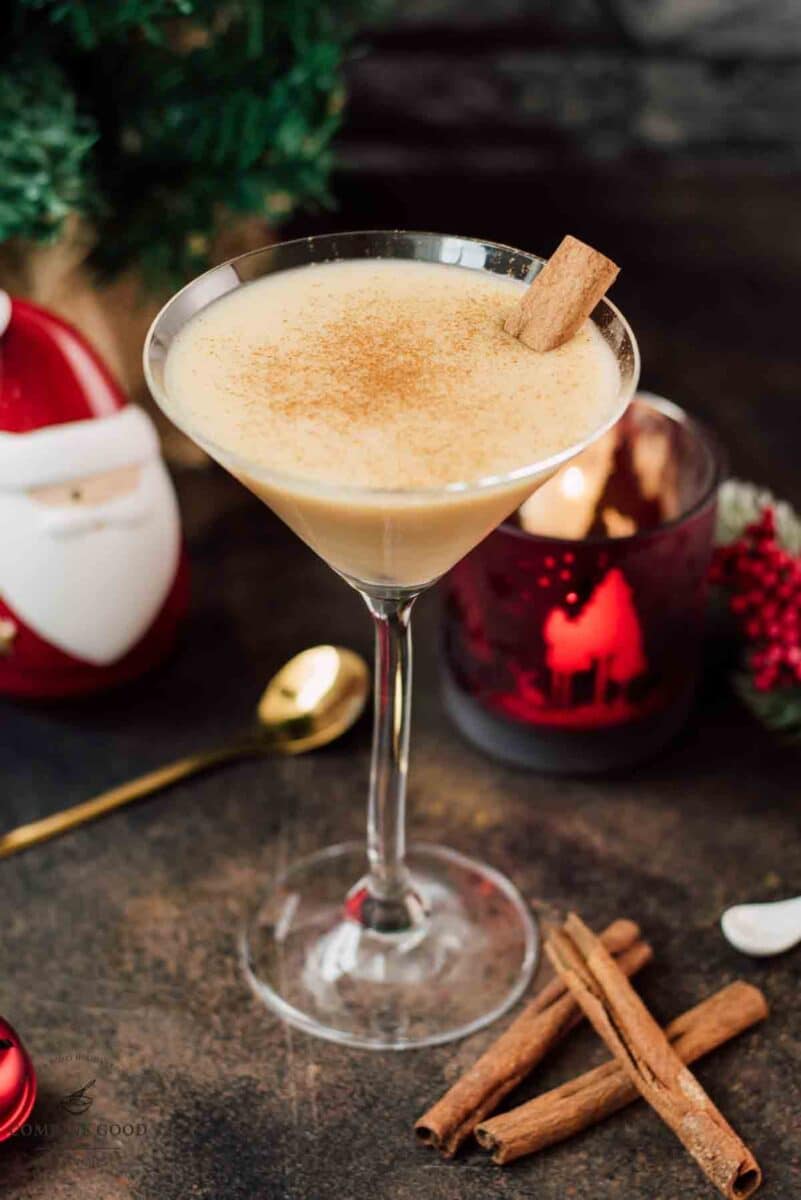 Delicious eggnog martini dusted with ground cinnamon and garnished with a cinnamon stick.