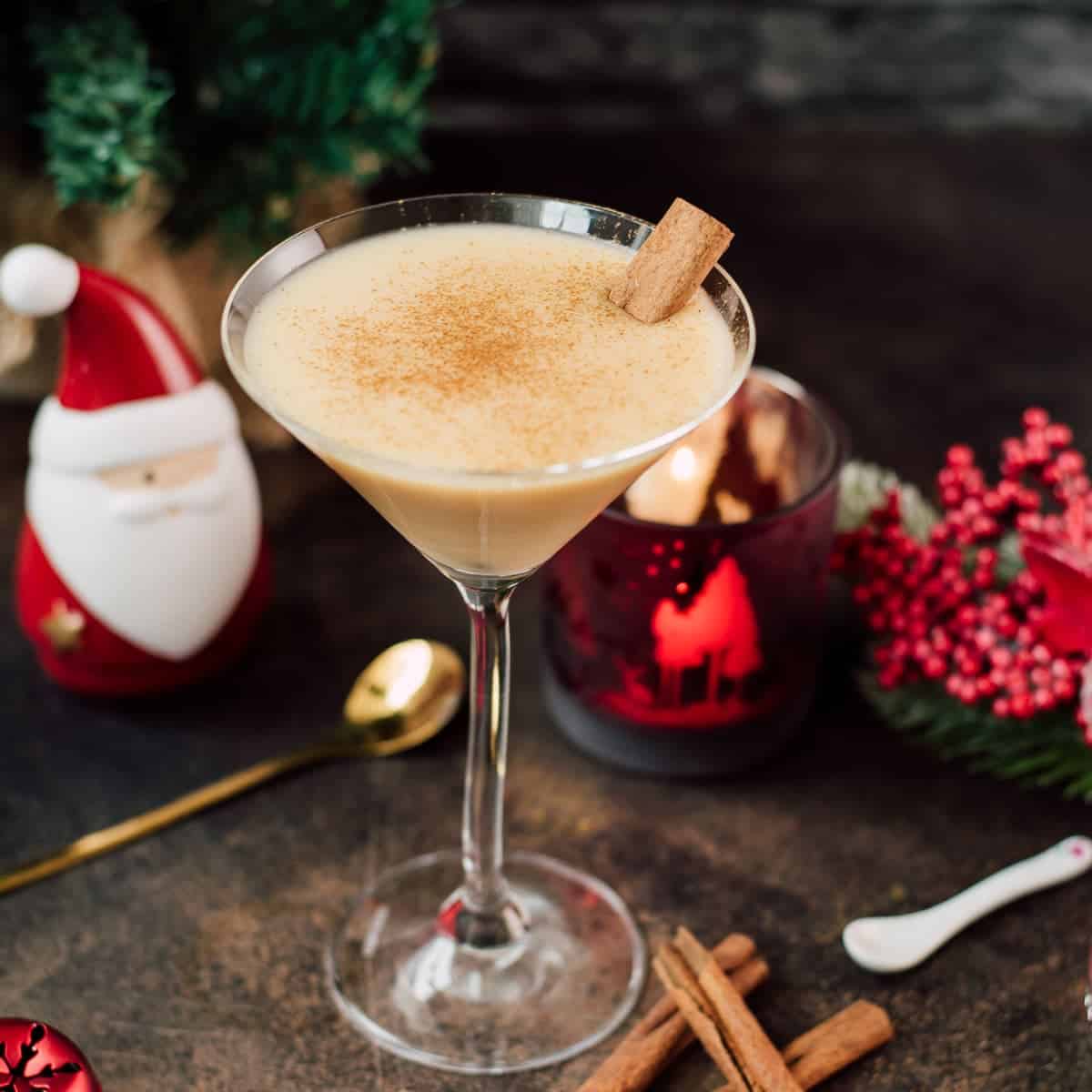Delicious eggnog martini dusted with ground cinnamon and garnished with a cinnamon stick.