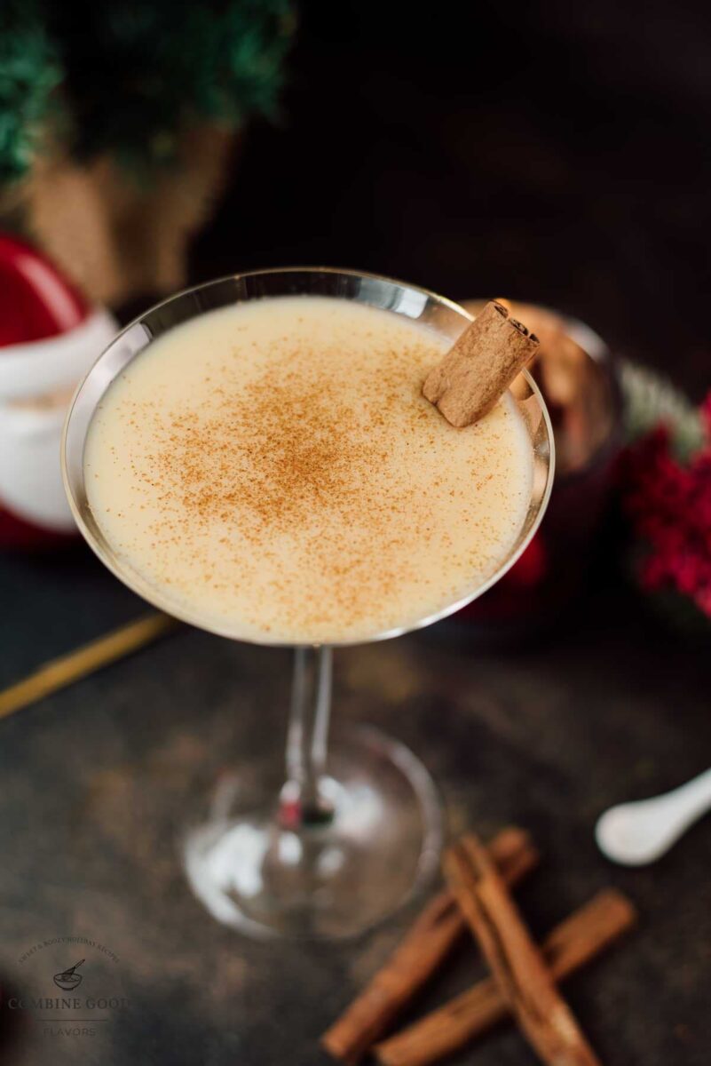 Delicious eggnog martini dusted with ground cinnamon and garnished with a cinnamon stick.