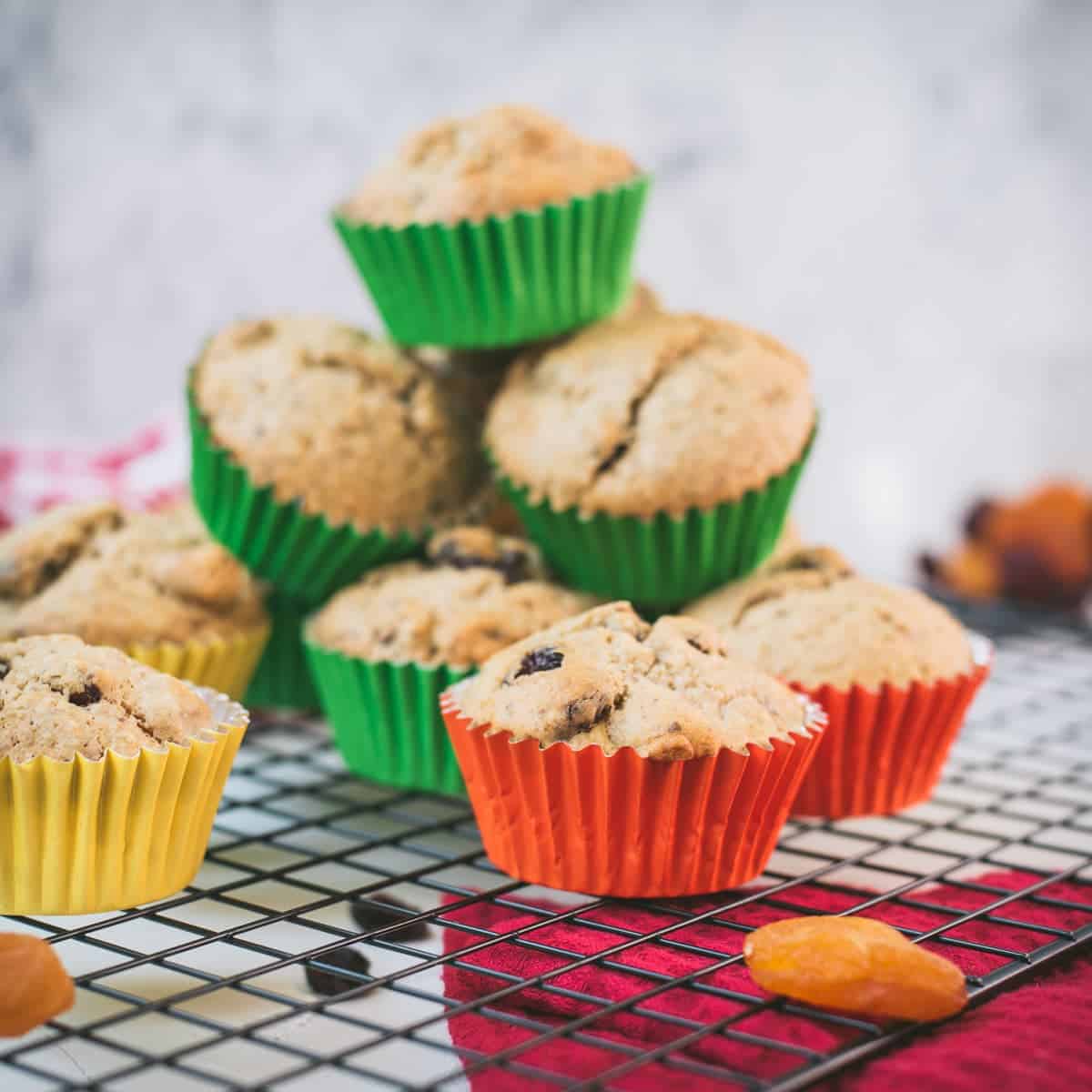 cute fruit and nut muffins with colored lines, stacked on cooling rack.