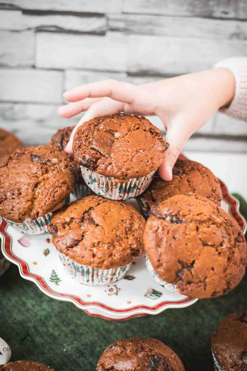 My daughters hand snagging delicious St. Nicholas chocolate muffins from christmassy plate.