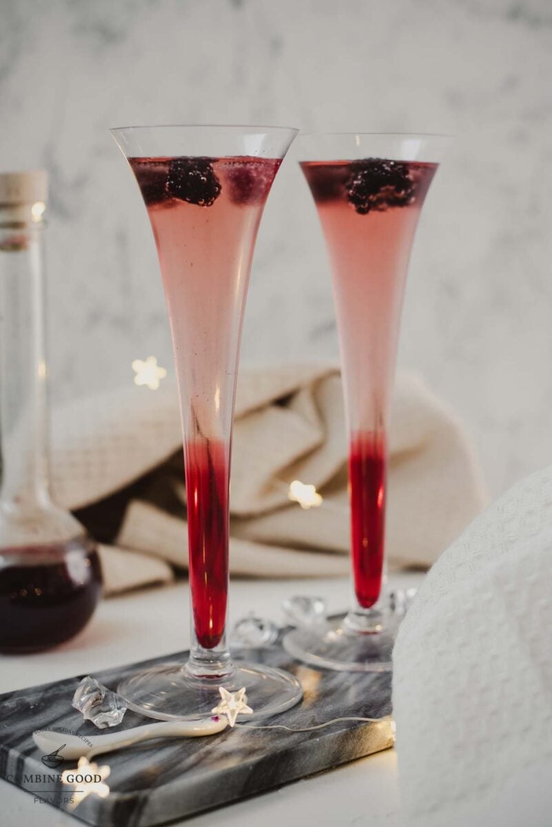 Champagne and chambord cocktail served in two champagne flutes. Garnished with berries.