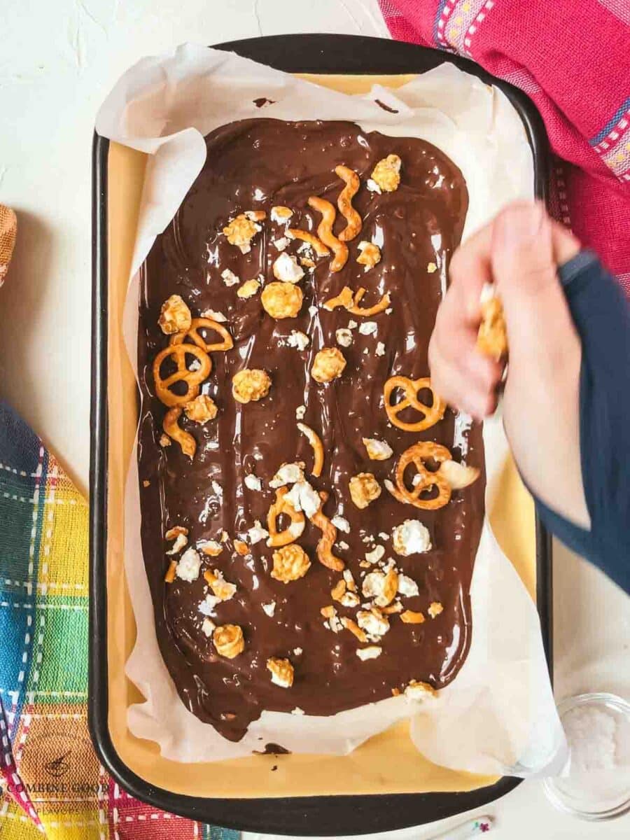 Sprinkle the crushed caramel popcorn and pretzels over the melted chocolate.
