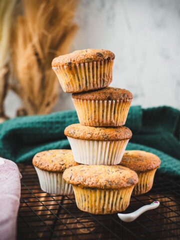 Delicious 4 egg yolk chocolate chip muffins stacked on cooling rack.