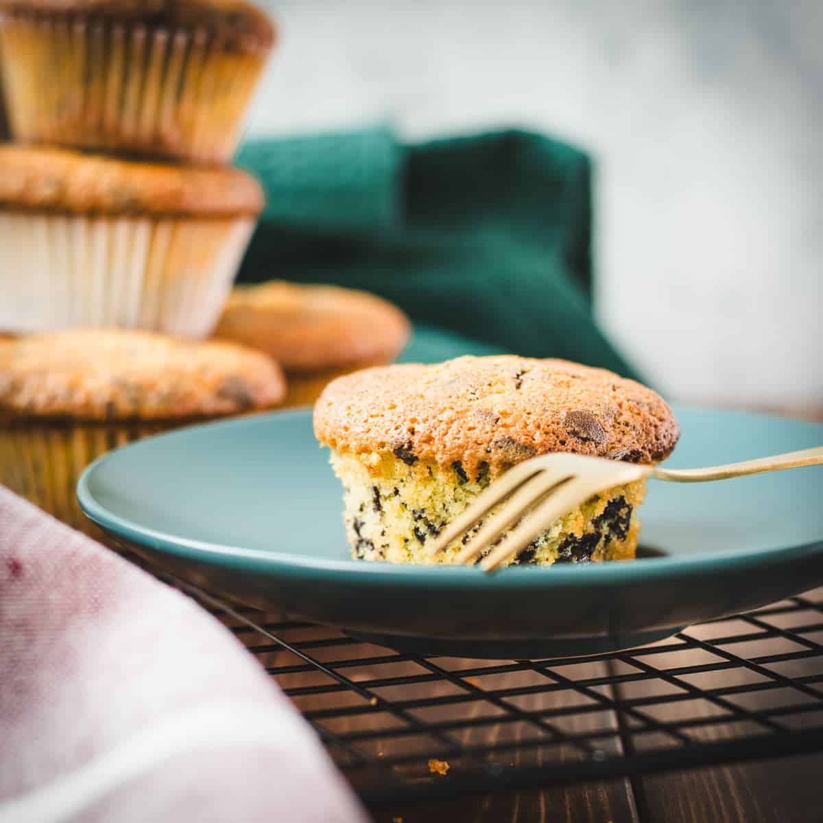 Delicious 4 egg yolk chocolate chip muffin placed on teal colored plate.