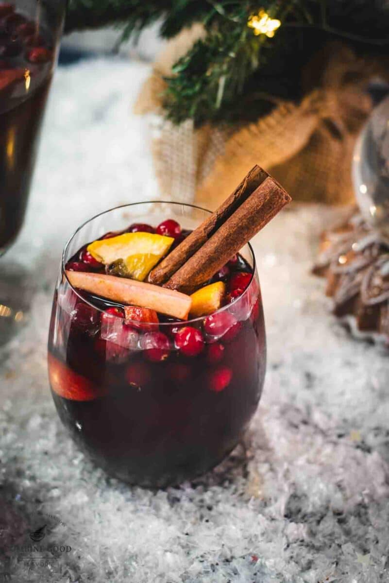 Gorgeous glass filled with delicious winter sangria, garnished with a cinnamon stick. Placed on snow covered ground.