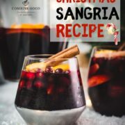 Gorgeous glass filled with delicious winter sangria, garnished with a cinnamon stick. Placed on snow covered ground.