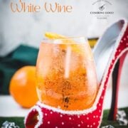 Aperol spritz with white wine instead of prosecco playfully served in a red and white polka dot high heel. Garnished with n orange slice.