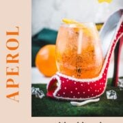 Aperol spritz with white wine instead of prosecco playfully served in a red and white polka dot high heel. Garnished with n orange slice.