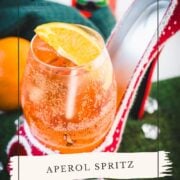 Aperol spritz with white wine instead of prosecco playfully served in a red and white polka dot high heel. Garnished with n orange slice.