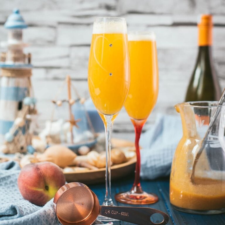 Beautiful champagne flutes, filled with delicious peach Bellini. Placed on blue, wooden ground.
