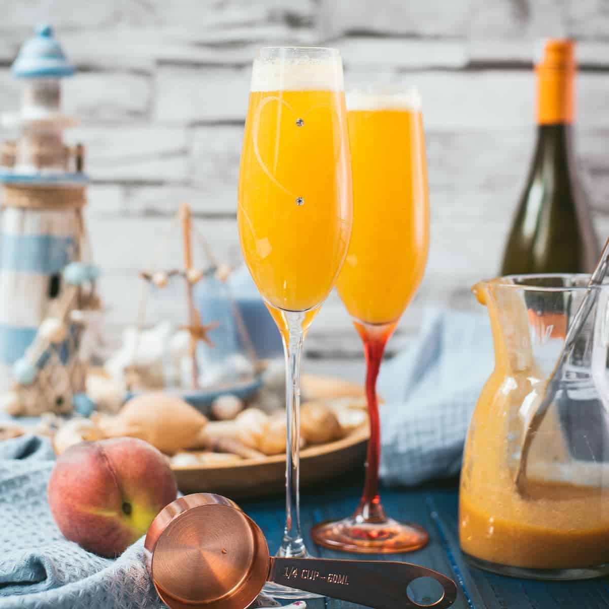 Beautiful champagne flutes, filled with delicious peach Bellini. Placed on blue, wooden ground.