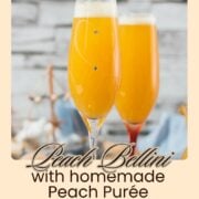 Beautiful champagne flutes, filled with delicious peach Bellini. Placed on blue, wooden ground.