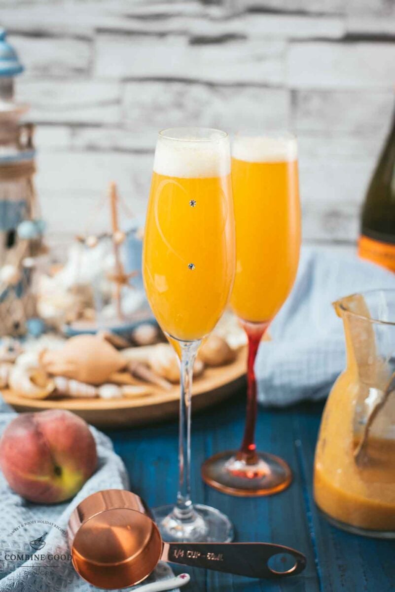 Beautiful champagne flutes, filled with delicious peach Bellini. Placed on blue, wooden ground.