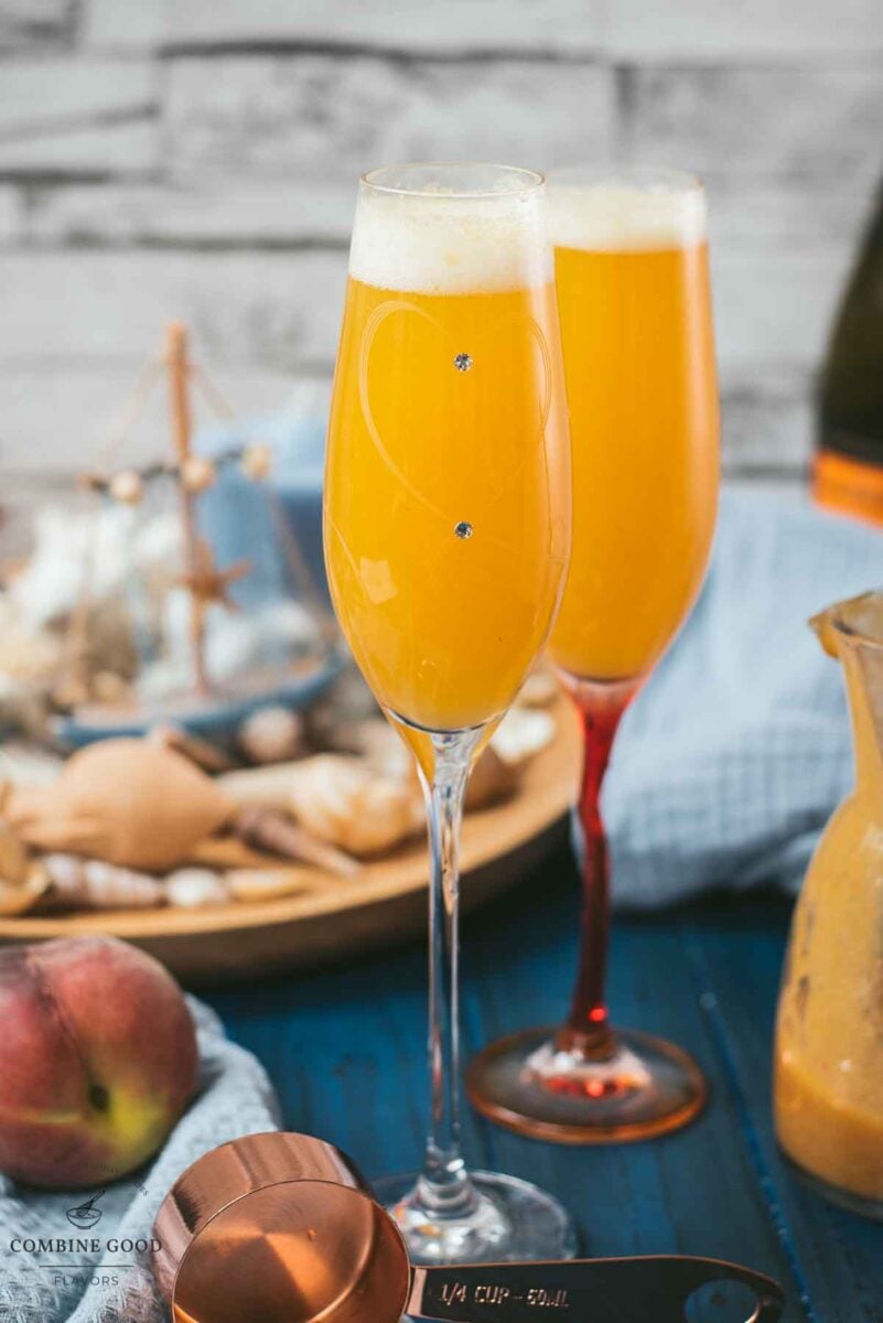 Beautiful champagne flutes, filled with delicious peach Bellini. Placed on blue, wooden ground.
