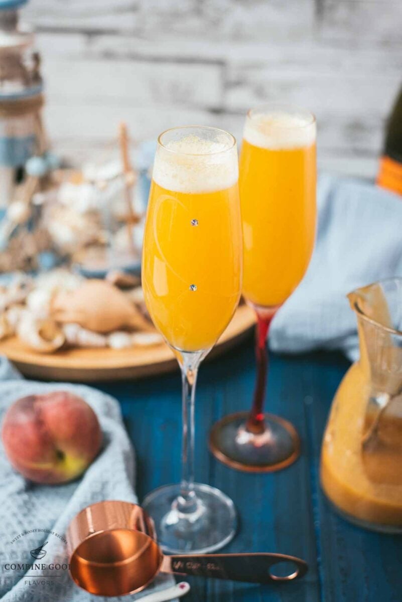 Beautiful champagne flutes, filled with delicious peach Bellini. Placed on blue, wooden ground.