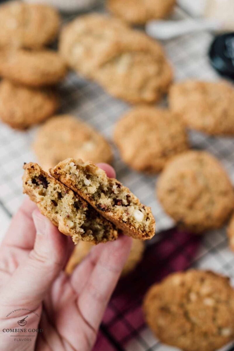 Holding two Raspberry macadamia oatmeal white chocolate chip cookie halves in one hand.