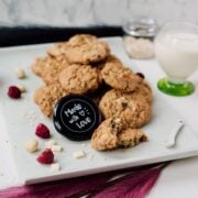 Raspberry macadamia oatmeal white chocolate chip cookies placed on white plate.