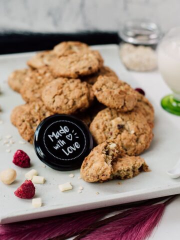 Raspberry macadamia oatmeal white chocolate chip cookies placed on white plate.