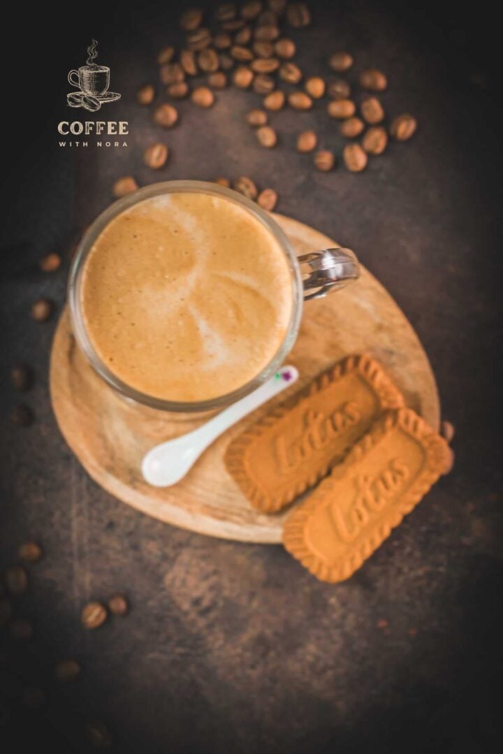 Super quick Biscoff Latte placed on small wooden plate next to two Biscoff cookies.