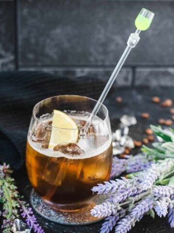 Delicious lavender cold brew cocktail with tonic water and vodka. Served in an gin tonic glass and garnished with a lemon slice.
