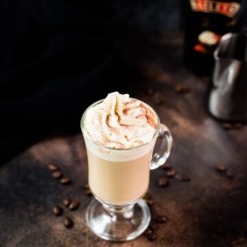 Decadent Bailey'S coffee, served in beautiful glass, placed on dark ground and topped with delicious whipped cream.