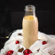 Christmas coffee creamer in preserving bottle, placed on white ground decorated with Christmas ornaments.