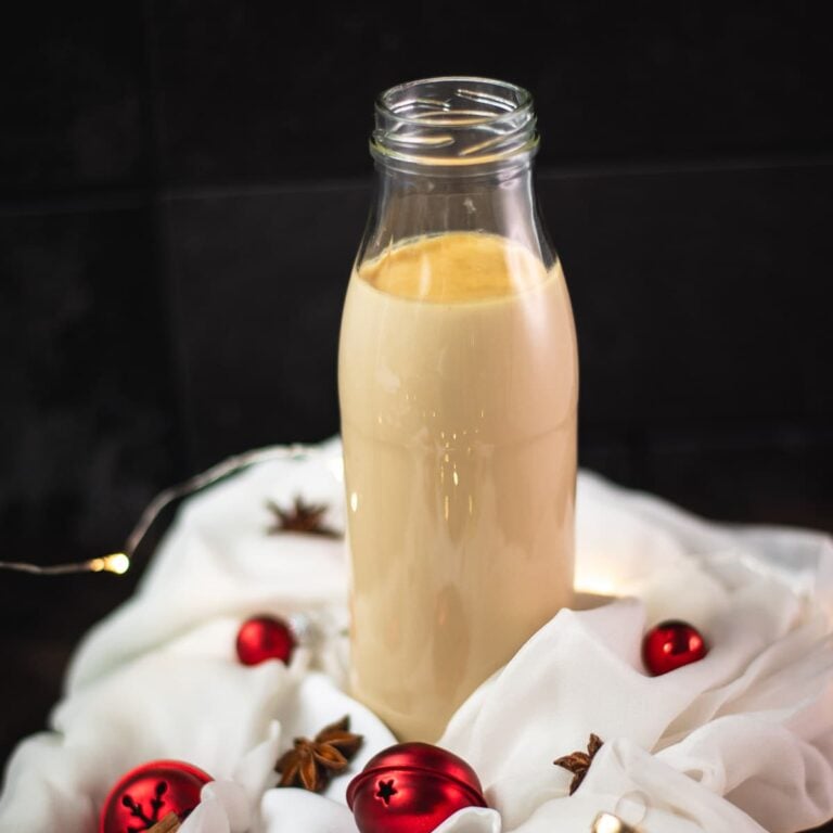 Christmas coffee creamer in preserving bottle, placed on white ground decorated with Christmas ornaments.