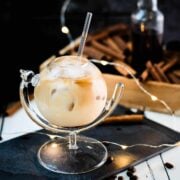 Gorgeous glass filled with iced cinnamon dolce latte, placed on black slate plate.