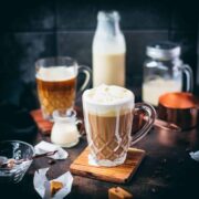 Beautiful glass filled with salted caramel coffee, placed on wooden coaster.