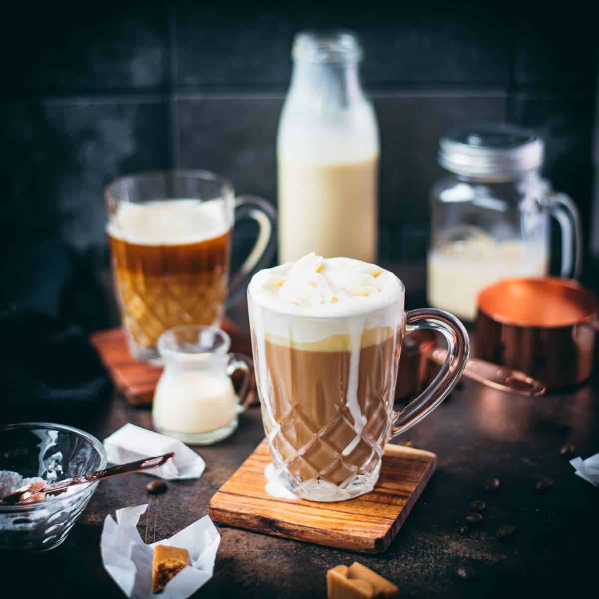Beautiful glass filled with salted caramel coffee, placed on wooden coaster.