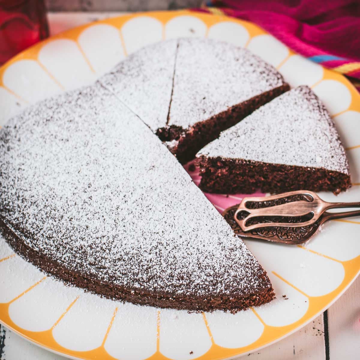 Delicious heart-shaped chocolate cake, dusted with powdered sugar. Ideal for Valentine's day! Placed on yellow-white serving plate.