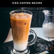 Gorgeous layered plant-based vanilla iced coffee, served in a beautiful glass, placed on a black slate plate.