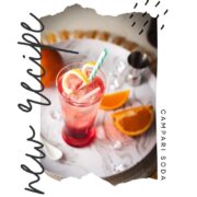 Divine Campari Soda, placed on marbled serving plate. Garnished with a lemon twist and served with a drinking straw.