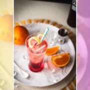 Divine Campari Soda, placed on marbled serving plate. Garnished with a lemon twist and served with a drinking straw.