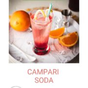 Divine Campari Soda, placed on marbled serving plate. Garnished with a lemon twist and served with a drinking straw.