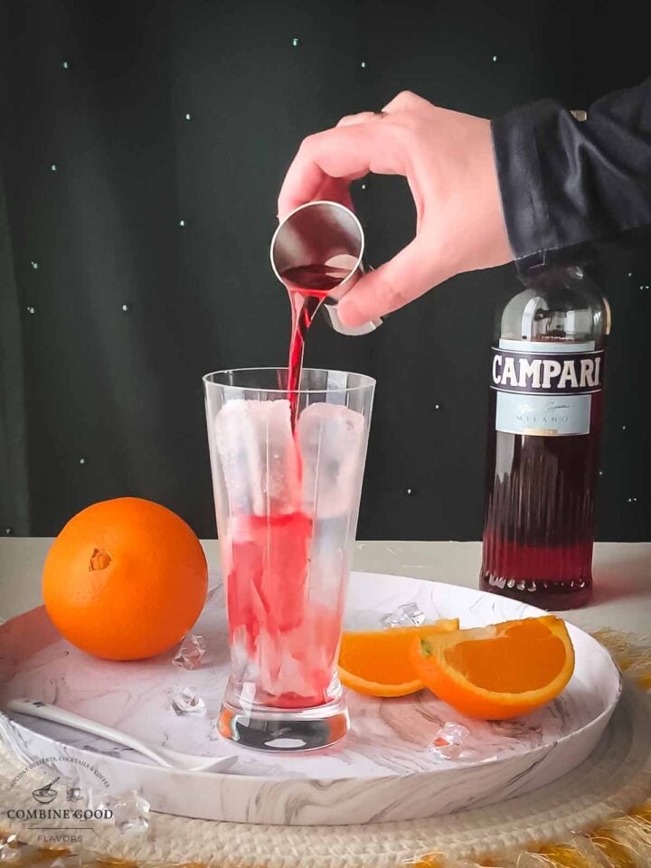 Add Campari to the cubed ice filled serving glass.