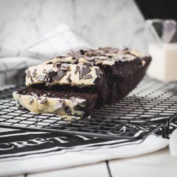 Divine chocolate buttermilk loaf cake with white chocolate frosting, sprinkled with chocolate shavings.
