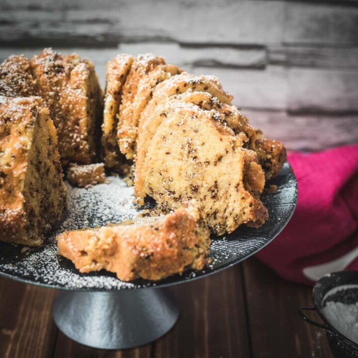 Delicious vanilla bundt cake with chocolate sprinkles, served on light blue cake stand.
