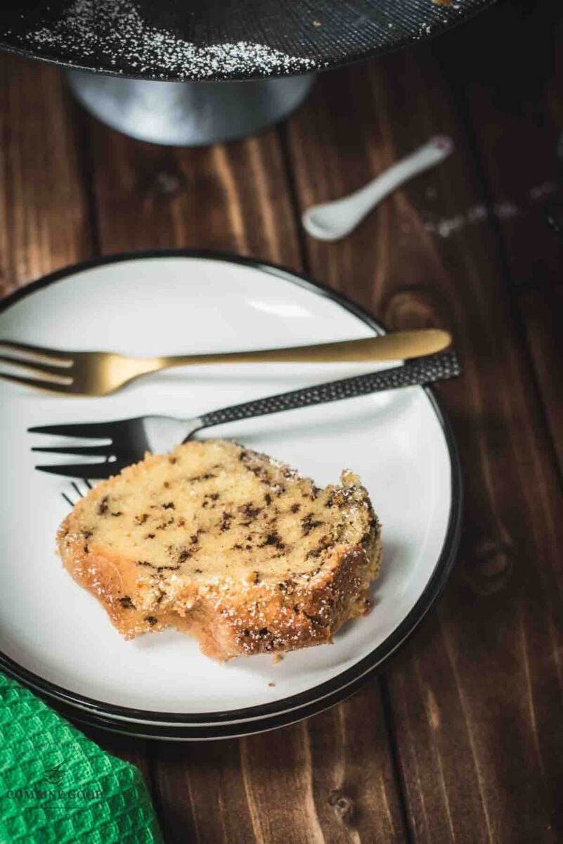 A slice of delicious vanilla bundt cake with chocolate sprinkles, served on a black and white plate.