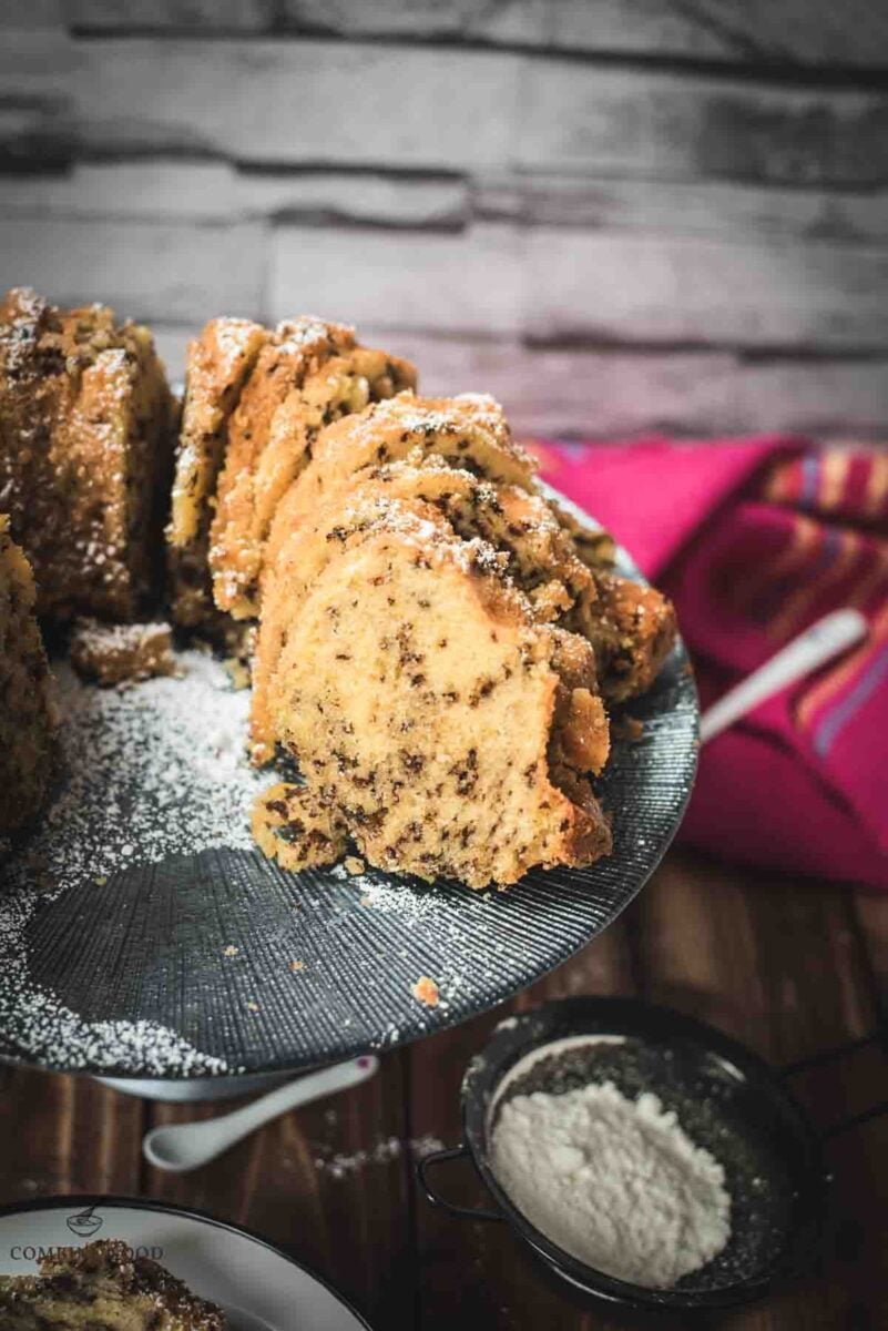 Delicious vanilla bundt cake with chocolate sprinkles, served on light blue cake stand.