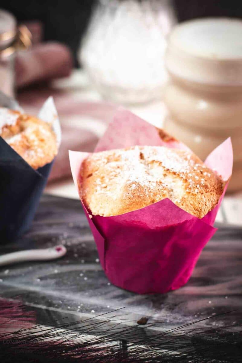 Cute angel food muffins, dusted with powdered sugar, placed on marbled plate and served with a delicious cafe latte.