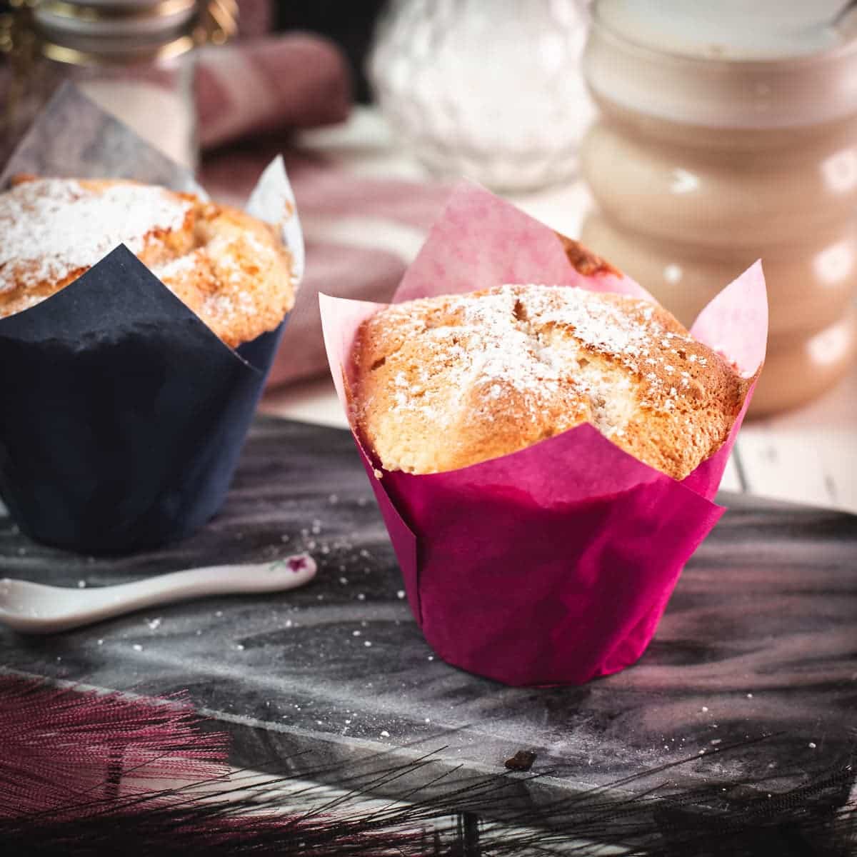 Cute angel food muffins, dusted with powdered sugar, placed on marbled plate and served with a delicious cafe latte.